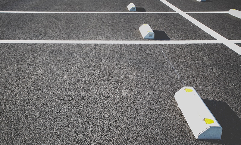 Concrete wheel stops (parking bumper blocks) arranged on asphalt parking area