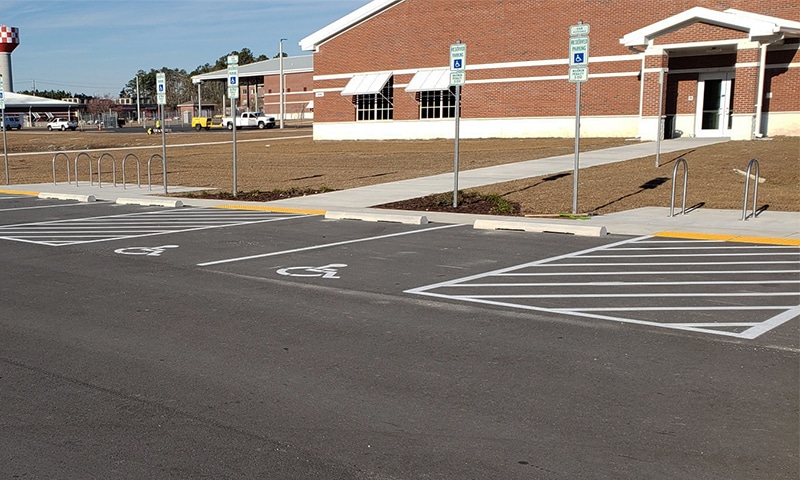 Parking lot signage post with directional and information signs in a paved lot with striping