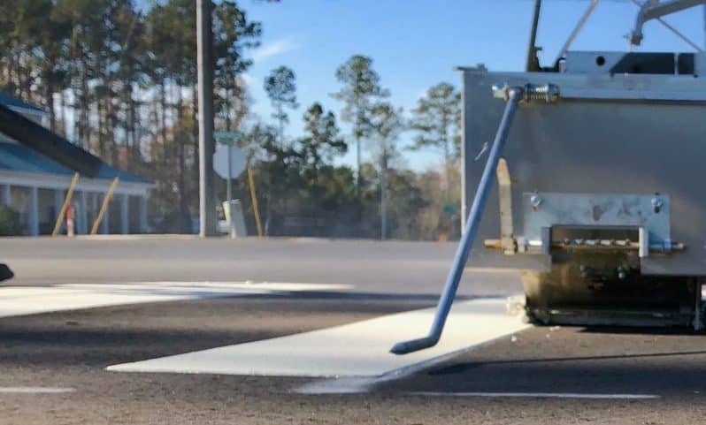 Fresh white pavement markings on asphalt in parking lot, showing directional arrows and boundary lines