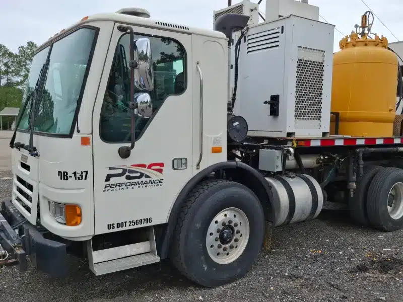 Performance Sealing & Striping service truck with mounted equipment and large yellow tank, parked on a gravel lot.